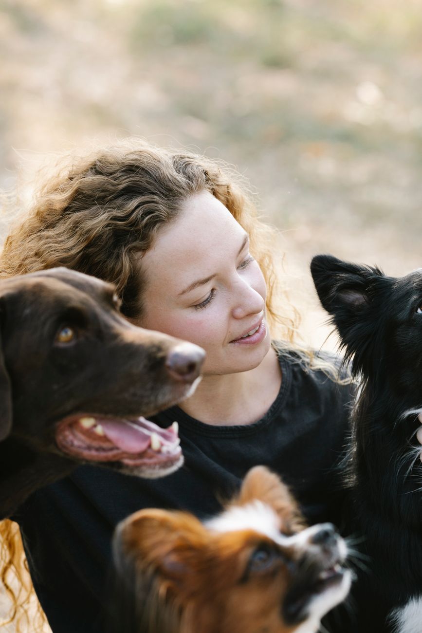 Founder Maren Holt kneeling beside two dogs in a sunlit entryway