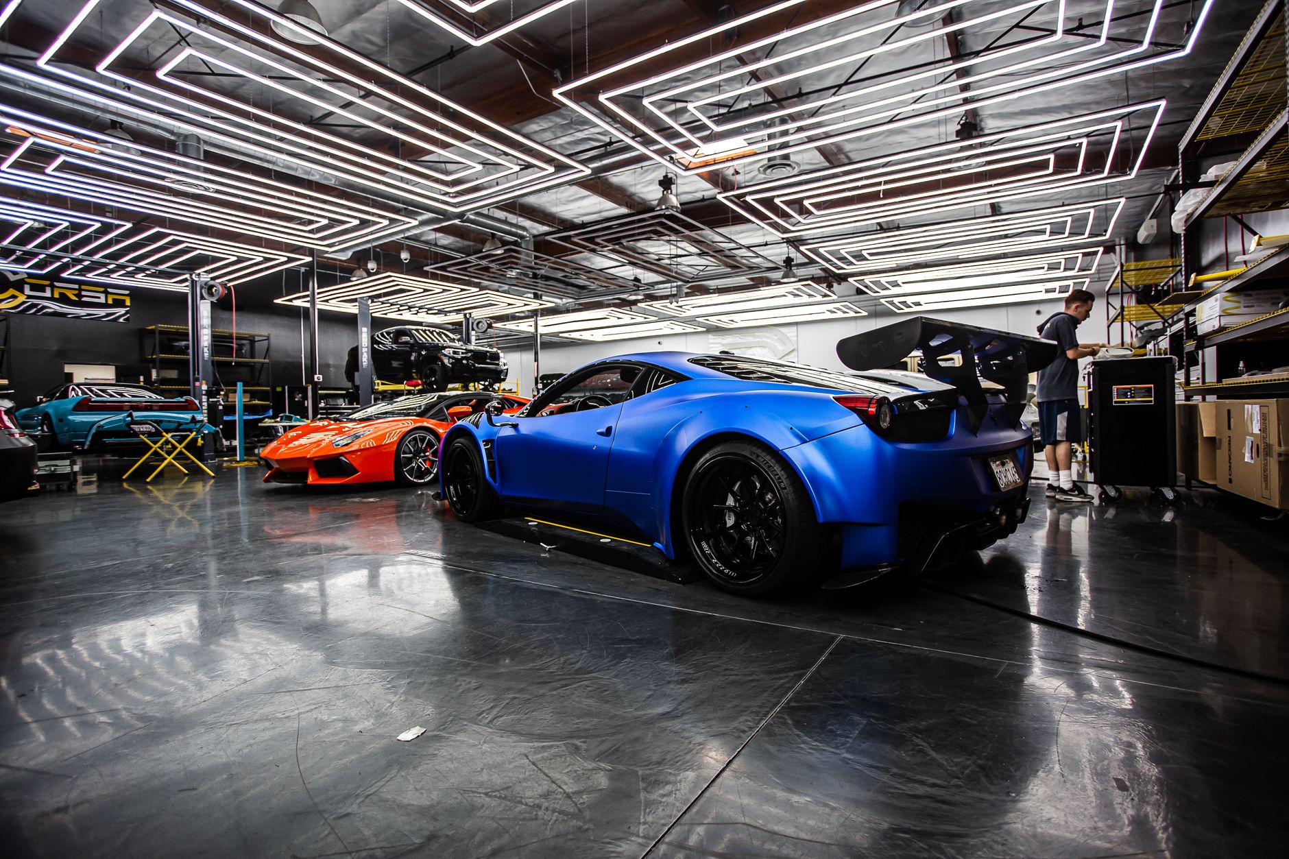 Detailer polishing a dark car under warm studio lights